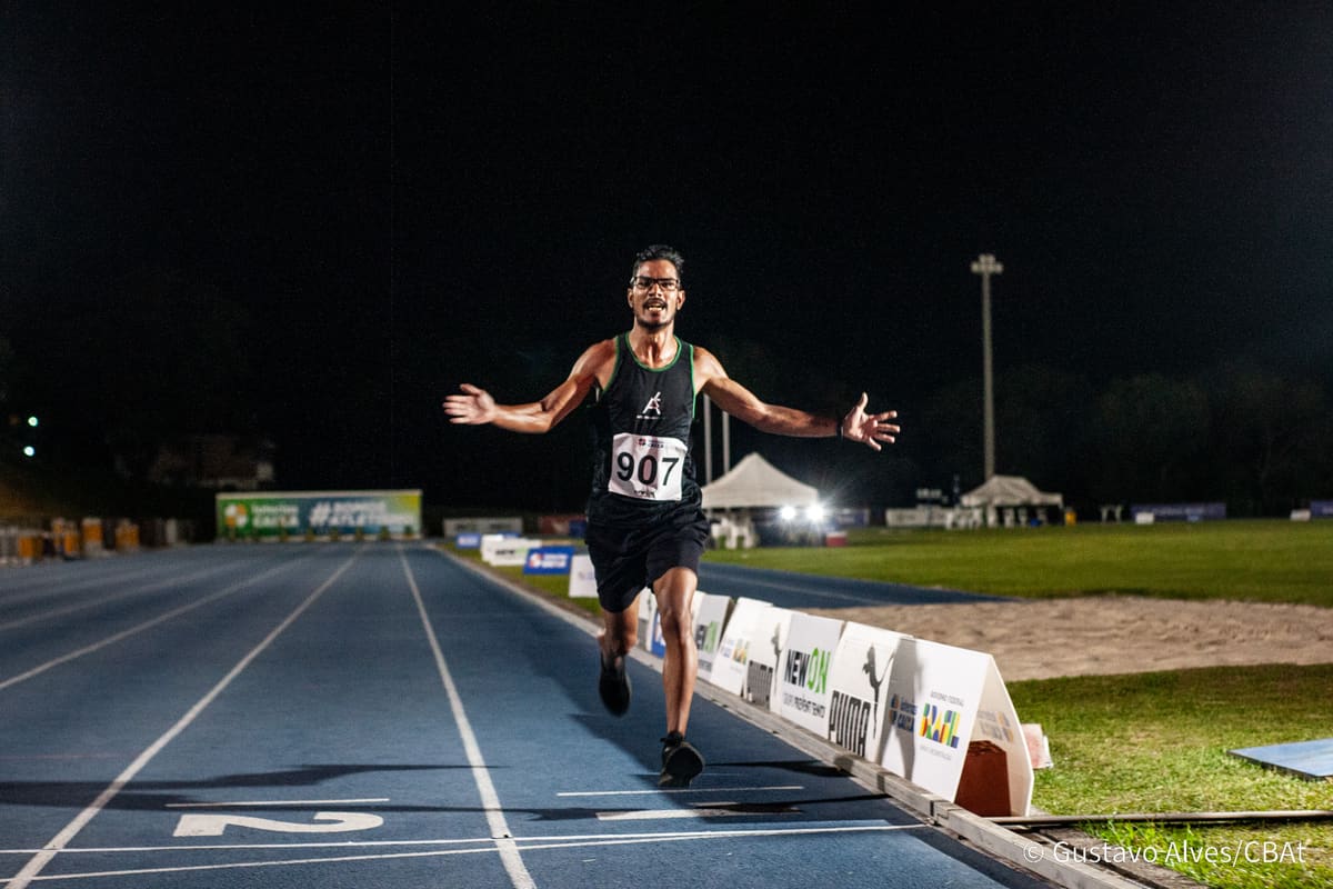 Atleta da Atletismo-UEM cruzando a linha de chegada em prova noturna